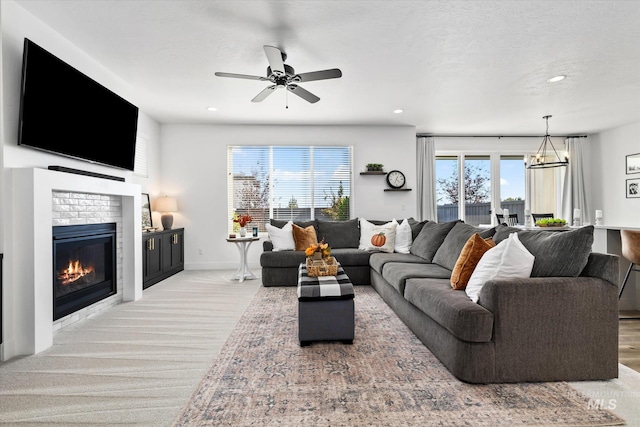 living area with a glass covered fireplace, recessed lighting, baseboards, and a textured ceiling