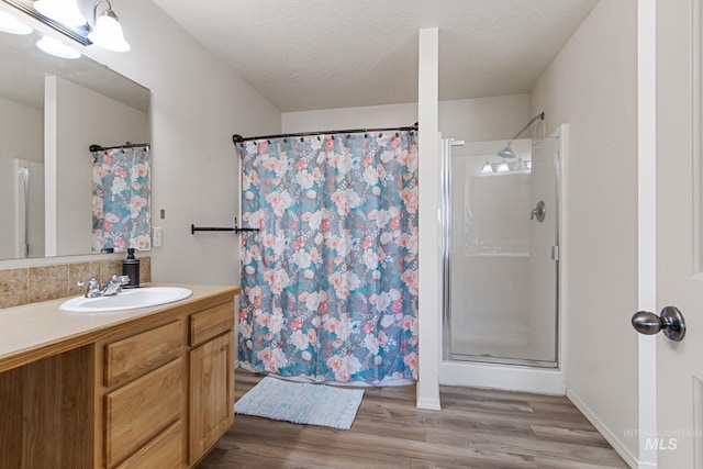 bathroom with a textured ceiling, a shower with curtain, wood-type flooring, and vanity