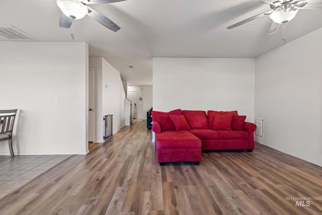 living room featuring a textured ceiling, ceiling fan, and wood-type flooring