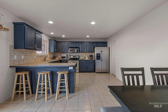 kitchen with stainless steel appliances, a kitchen breakfast bar, backsplash, kitchen peninsula, and blue cabinets