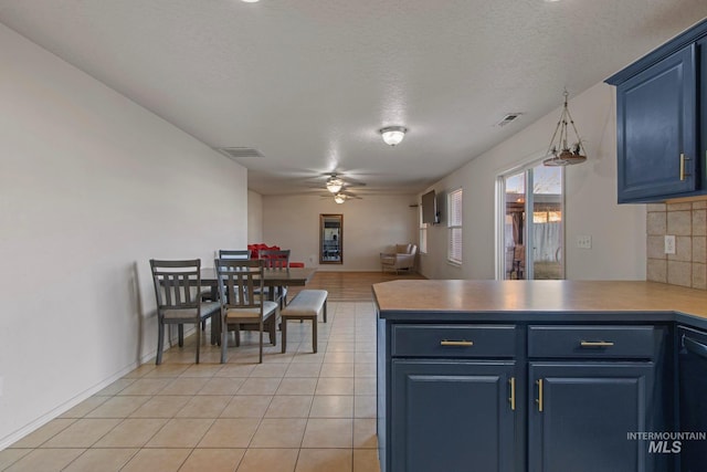 kitchen featuring decorative light fixtures, blue cabinetry, a textured ceiling, and tasteful backsplash