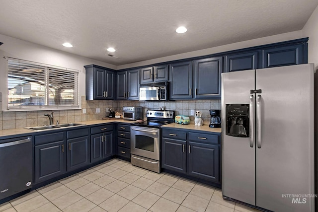 kitchen with light tile patterned floors, sink, backsplash, and appliances with stainless steel finishes