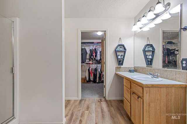 bathroom with a textured ceiling, a shower with door, hardwood / wood-style flooring, and vanity