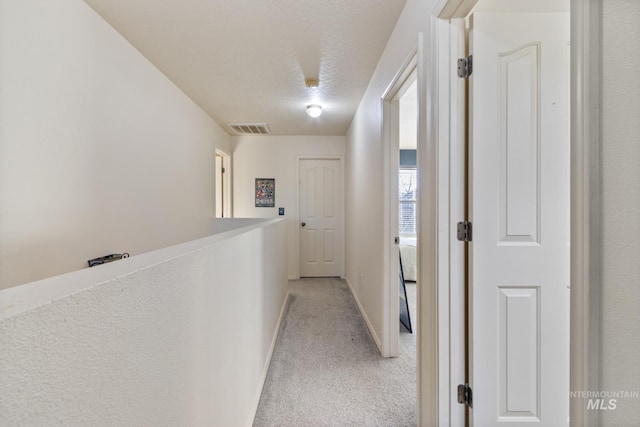 hall with a textured ceiling and light carpet