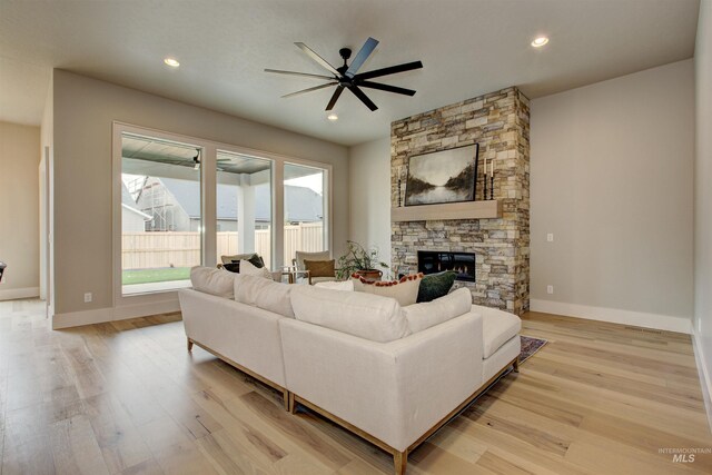 living room featuring ceiling fan, light hardwood / wood-style flooring, and a fireplace