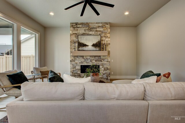 living room featuring ceiling fan, a brick fireplace, and light hardwood / wood-style floors