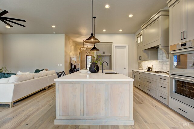 kitchen with an island with sink, pendant lighting, decorative backsplash, and gray cabinets