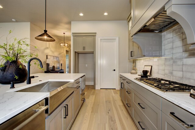 kitchen with light stone countertops, sink, hanging light fixtures, and a stone fireplace