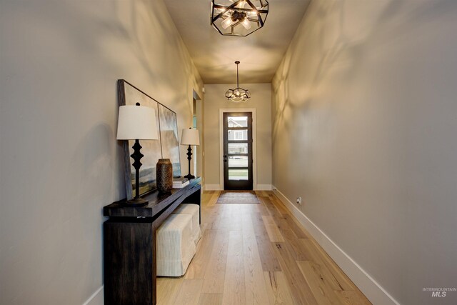 corridor featuring light hardwood / wood-style flooring and a notable chandelier