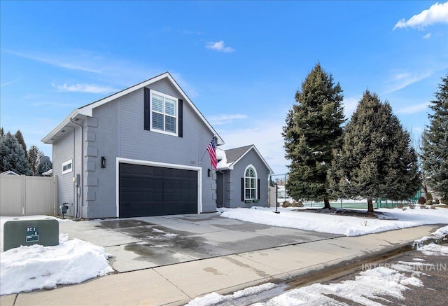 traditional-style home with an attached garage, driveway, and fence