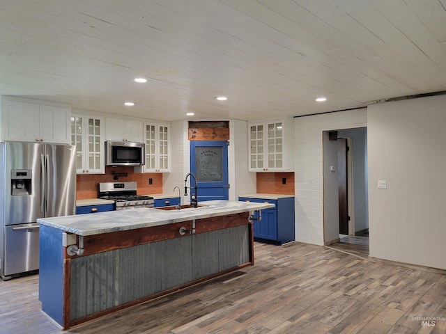 kitchen featuring white cabinetry, an island with sink, wood-type flooring, and appliances with stainless steel finishes