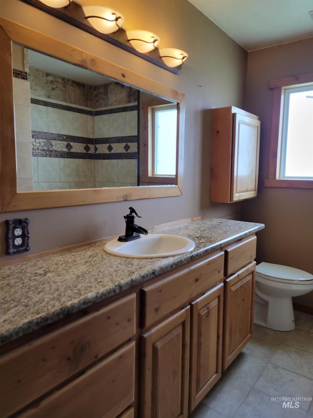 bathroom featuring tile patterned flooring, vanity, toilet, and tiled shower