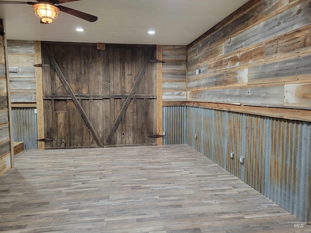 interior space featuring a barn door, hardwood / wood-style flooring, and wood walls