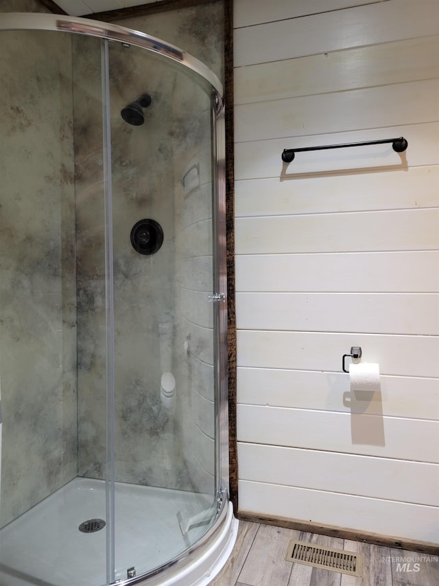 bathroom with wooden walls, hardwood / wood-style floors, and a shower with door