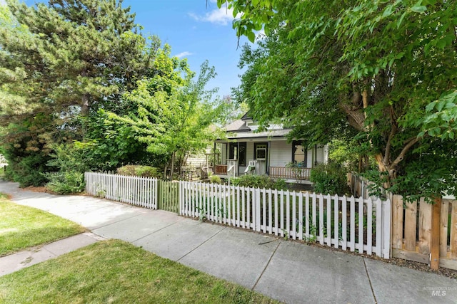 view of property hidden behind natural elements featuring covered porch