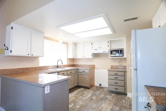 1120 SW 14th Ave, Ontario, OR 97914 - kitchen featuring freestanding refrigerator, under cabinet range hood, light wood-style flooring, a peninsula, and stainless steel microwave