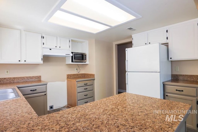 1120 SW 14th Ave, Ontario, OR 97914 - kitchen featuring freestanding refrigerator, stainless steel microwave, under cabinet range hood, and white cabinets