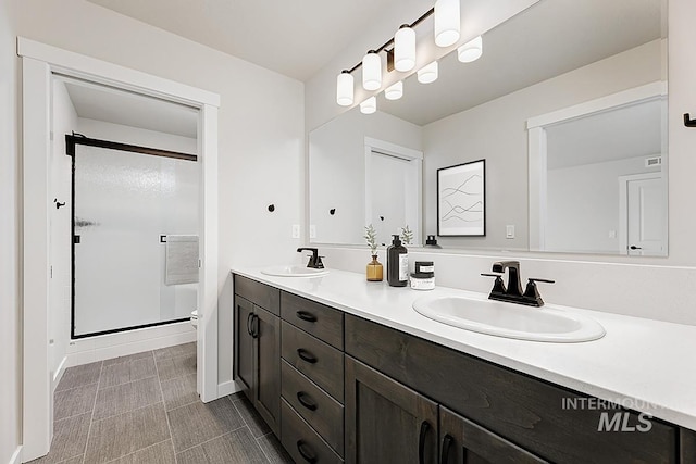 full bath featuring a shower stall, double vanity, toilet, and baseboards