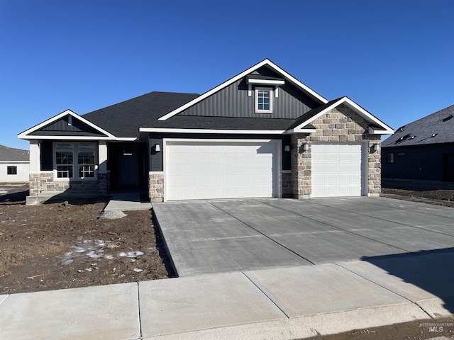 craftsman-style home with driveway, an attached garage, board and batten siding, and stone siding