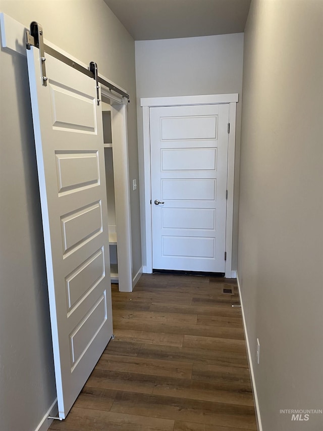 entryway featuring a barn door, baseboards, and dark wood finished floors