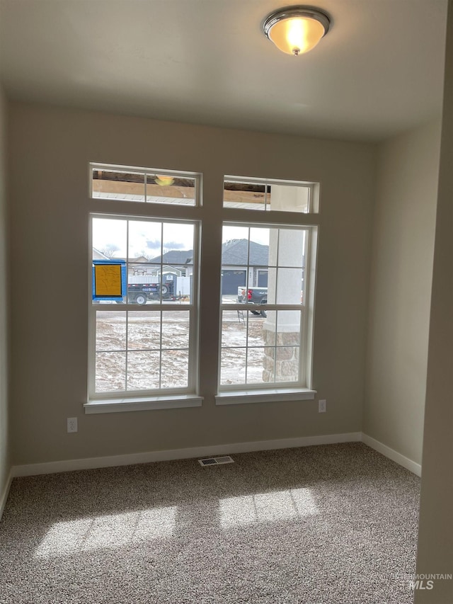 carpeted empty room featuring visible vents and baseboards