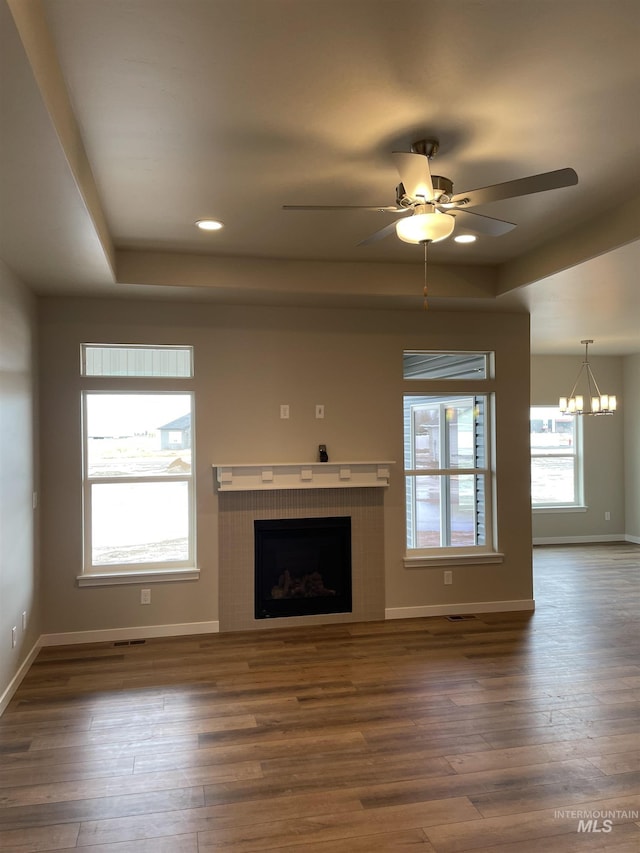 unfurnished living room featuring baseboards, a raised ceiling, wood finished floors, and a fireplace