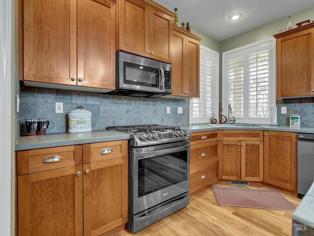 1546 N Dragonfly Ct, Eagle, ID 83616 - kitchen with decorative backsplash, appliances with stainless steel finishes, light countertops, a sink, and light wood-type flooring
