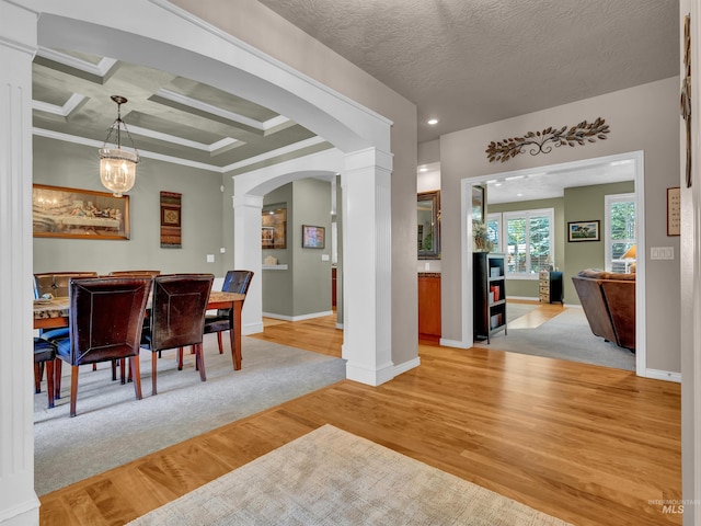 1546 N Dragonfly Ct, Eagle, ID 83616 - dining space featuring arched walkways, coffered ceiling, decorative columns, light wood finished floors, and baseboards