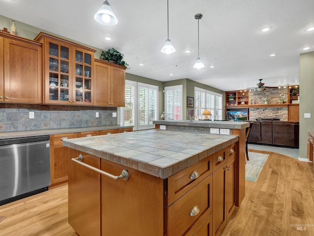 1546 N Dragonfly Ct, Eagle, ID 83616 - kitchen with brown cabinetry, tasteful backsplash, light wood-style flooring, a kitchen island, and stainless steel dishwasher