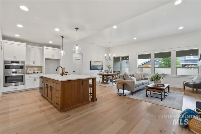 11270 S Saylis Way, Kuna, ID 83634 - kitchen with open floor plan, stainless steel appliances, light wood-style floors, white cabinetry, and recessed lighting