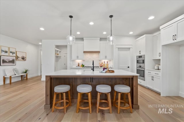 11270 S Saylis Way, Kuna, ID 83634 - kitchen featuring stainless steel double oven, white cabinetry, light countertops, light wood finished floors, and recessed lighting