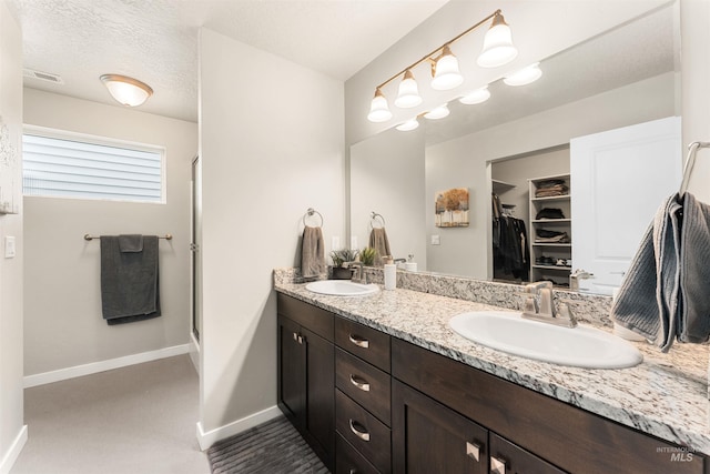 3065 E Ionia Ct, Meridian, ID 83642 - full bathroom with double vanity, a walk in closet, baseboards, a shower stall, and a textured ceiling