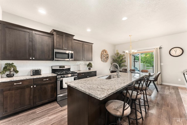3065 E Ionia Ct, Meridian, ID 83642 - kitchen with stainless steel appliances, a sink, wood finished floors, a chandelier, and backsplash