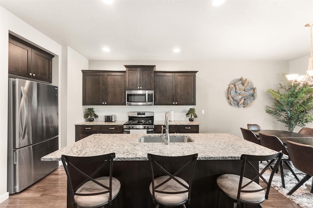 3065 E Ionia Ct, Meridian, ID 83642 - kitchen with appliances with stainless steel finishes, a sink, wood finished floors, a breakfast bar area, and dark brown cabinetry