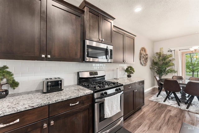 3065 E Ionia Ct, Meridian, ID 83642 - kitchen with appliances with stainless steel finishes, dark wood finished floors, baseboards, decorative backsplash, and a textured ceiling