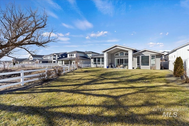 rear view of house with a residential view, fence, and a yard