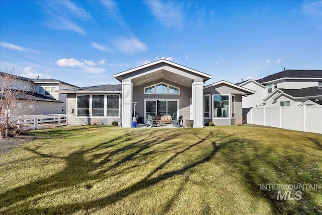 rear view of house featuring a yard, a patio, and a fenced backyard