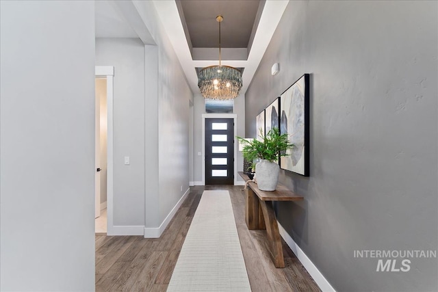 interior space with a chandelier, wood finished floors, and baseboards