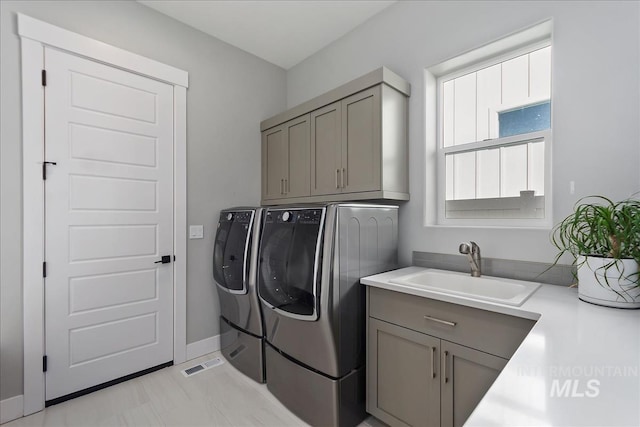 laundry area featuring cabinet space, a sink, washer and clothes dryer, and baseboards