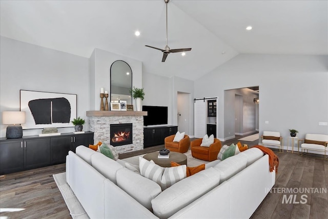 living area with a barn door, a ceiling fan, wood finished floors, a fireplace, and recessed lighting