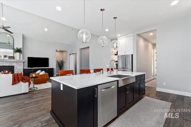 kitchen featuring dark wood finished floors, a fireplace, light countertops, appliances with stainless steel finishes, and a sink