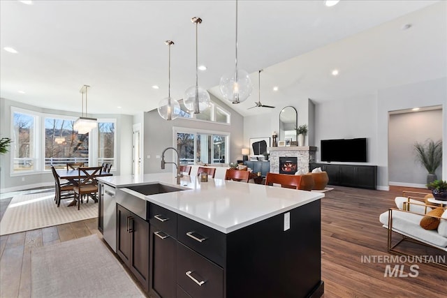 kitchen featuring dark wood-type flooring, a fireplace, a sink, light countertops, and dishwasher