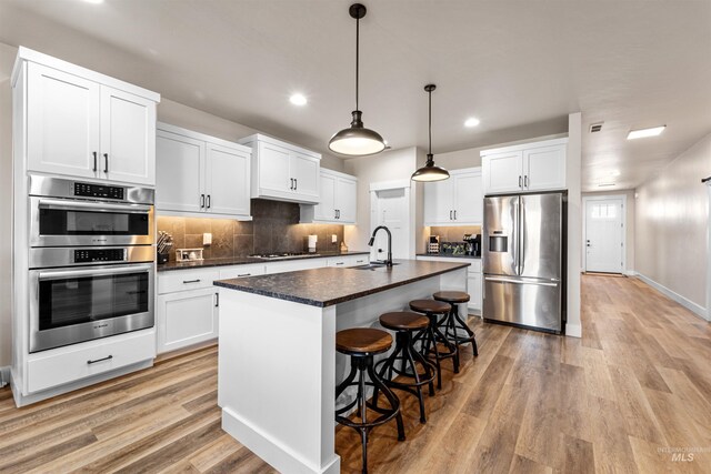 3056 E Columbus River Ct, Nampa, ID 83686 - kitchen with dark countertops, recessed lighting, white cabinetry, light wood-style flooring, and stainless steel appliances
