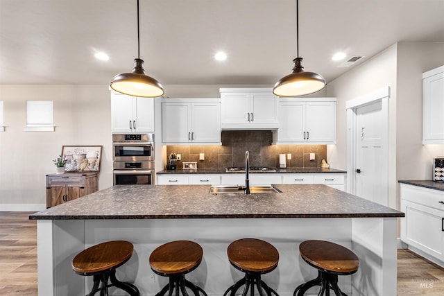 3056 E Columbus River Ct, Nampa, ID 83686 - kitchen with a sink, a kitchen breakfast bar, light wood-style flooring, stainless steel appliances, and tasteful backsplash