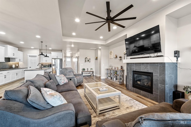 3056 E Columbus River Ct, Nampa, ID 83686 - living room featuring ceiling fan, recessed lighting, a raised ceiling, a tile fireplace, and light wood-style flooring