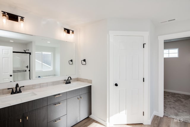 bathroom featuring double vanity, visible vents, walk in shower, and a sink