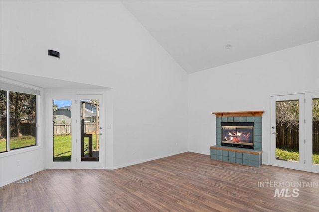 2702 N Camden Pl, Boise, ID 83704 - unfurnished living room with high vaulted ceiling, wood finished floors, a tiled fireplace, baseboards, and visible vents