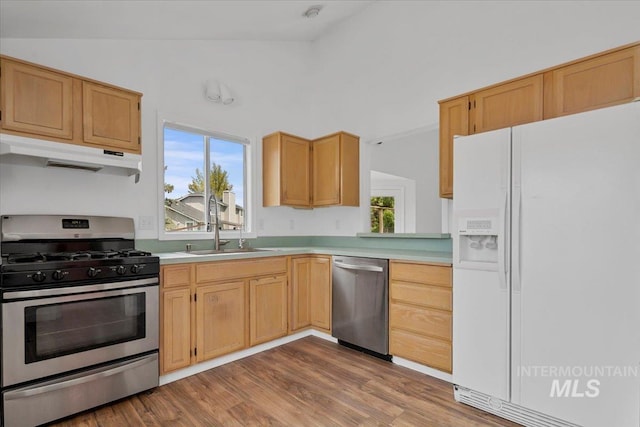 2702 N Camden Pl, Boise, ID 83704 - kitchen featuring under cabinet range hood, stainless steel appliances, light countertops, vaulted ceiling, and a sink