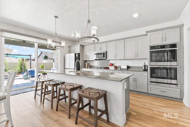 11211 Sopris Loop, Caldwell, ID 83605 - kitchen featuring stainless steel appliances, a chandelier, gray cabinets, tasteful backsplash, and a center island with sink