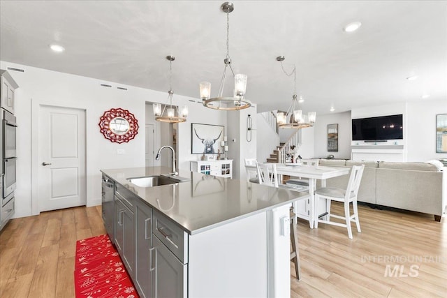 11211 Sopris Loop, Caldwell, ID 83605 - kitchen featuring a sink, a chandelier, light wood-type flooring, appliances with stainless steel finishes, and an island with sink